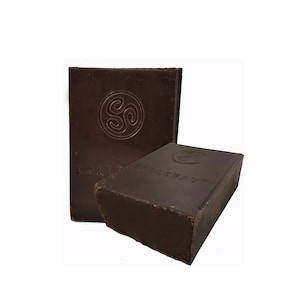 May include: Two dark brown rectangular bars of soap. One bar is upright, and the other is leaning against it. Each bar has a circular embossed design and the word "CALLE" embossed on it.