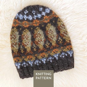 May include: A knit beanie featuring a dark brown ribbed brim and a multi-coloured fair isle pattern in shades of light blue, olive green, and burnt orange. The text KNITTING PATTERN is printed in white on a dark grey square overlay at the bottom.
