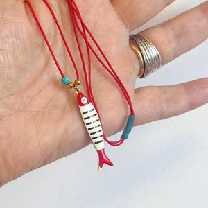 Bright red cord with adjustable length - Enamel sardine charm inspired by Portuguese coast - Tiny turquoise bead accent

🌊 Easy, boho coastal styling for summer