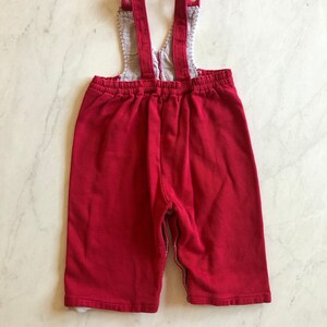 Puede incluir: Peto de beb&eacute; de pana rojo con tirantes ajustables. El peto tiene un forro estampado en contraste visible en el peto y los pu&ntilde;os. Los tirantes se abrochan con botones.