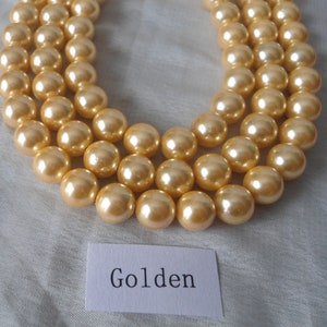 May include: A strand of golden pearl beads, with the word "Golden" written on a white card below.