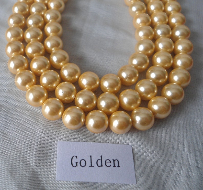 May include: A strand of golden pearl beads, with the word "Golden" written on a white card below.