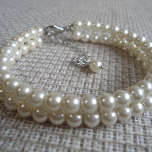 May include: A double strand pearl bracelet with a silver clasp and a small pearl charm.