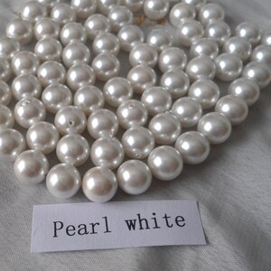 May include: A strand of white pearl beads. The beads are round and smooth, and they are arranged in a loose, flowing pattern. The beads are all the same size, and they are strung on a clear thread. The beads are arranged in a loose, flowing pattern. The beads are all the same size, and they are strung on a clear thread. The text "Pearl white" is written on a white card.