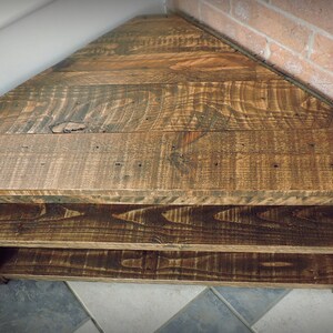 May include: A wooden corner shelf with two shelves. The shelf is made of reclaimed wood and has a rustic finish.