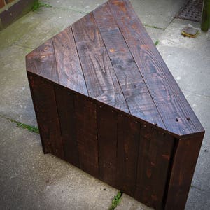 May include: A dark brown triangular wooden coffee table made from reclaimed wood planks.