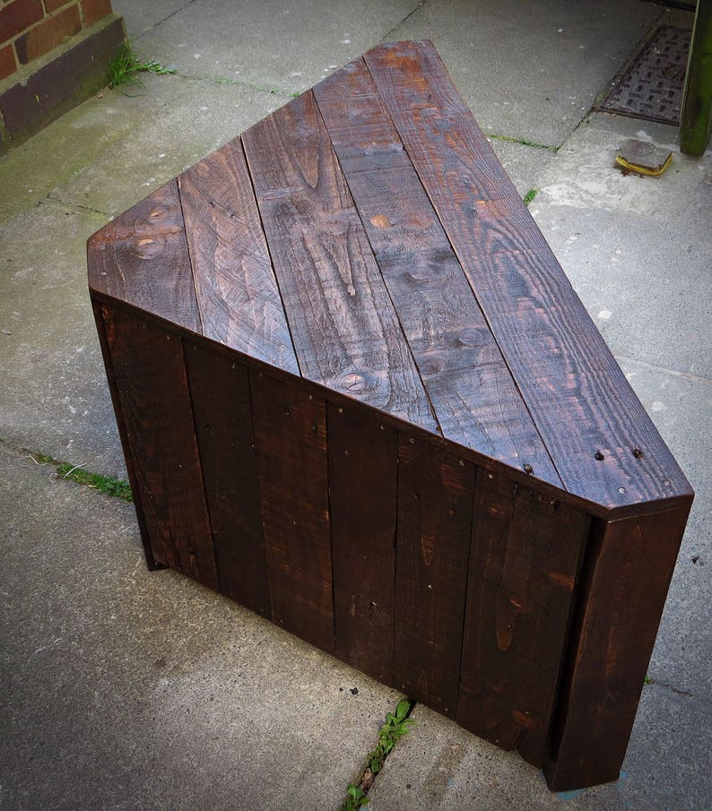 May include: A dark brown triangular wooden coffee table made from reclaimed wood planks.