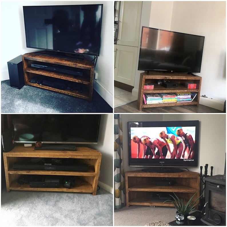 May include: A corner TV stand made of reclaimed wood with two shelves. The stand is shown with a TV on top and a sound bar on the bottom shelf. The stand is a dark brown color and has a rustic look.