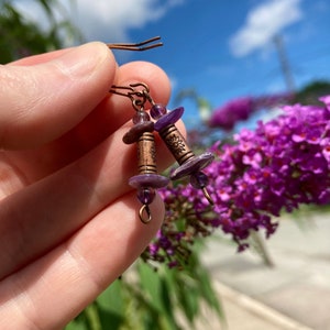 May include: Purple and copper earrings with a flower design. The earrings are made with amethyst beads and copper wire.