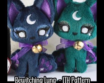 May include: Two plush cat toys, one blue and one green, with purple ears and a crescent moon on their foreheads. Both have sparkly eyes and a gold bell around their necks. The text "Bewitching Luna -  ITH Pattern" is at the bottom of the image.