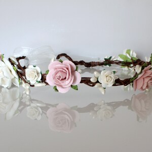 May include: A delicate floral crown with pink and white roses, pearl accents, and brown vines.