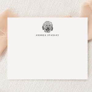May include: A white rectangular stationery card featuring a black and white line drawing of a dog's face centered at the top. Below the illustration, the name ANDREA STANLEY is printed in a clean, black, uppercase serif font.