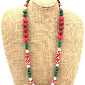 May include: A long, multi-colored beaded necklace with red, white, and green beads. The necklace is made of wooden beads with a variety of patterns.