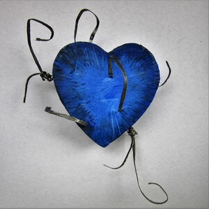 May include: A blue heart-shaped object with black wire wrapped around it. The heart is painted with a blue and white swirl pattern.