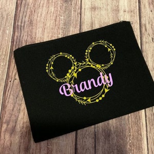 May include: Black zippered pouch with a yellow and gold Mickey Mouse head design and the name "Brandy" in pink lettering.