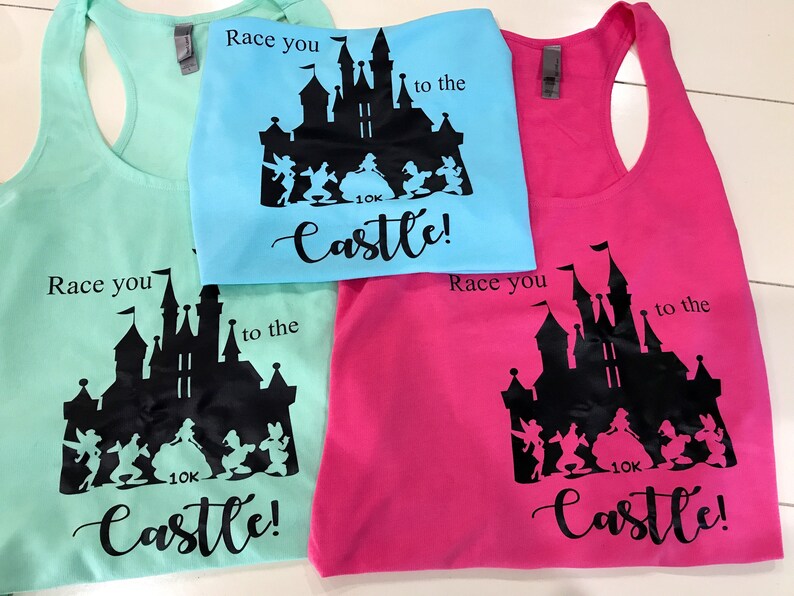May include: Three tank tops with a black silhouette of Cinderella's castle and the text "Race you to the castle!" printed on them. The tank tops are in turquoise, light blue, and pink.