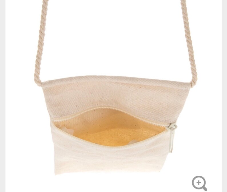 May include: A white canvas crossbody bag with a zipper closure and a rope strap.