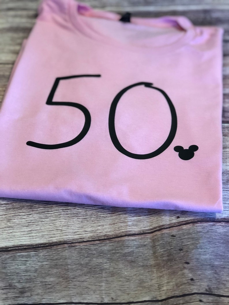 May include: A pink t-shirt with the number 50 printed in black and a small black Mickey Mouse silhouette.