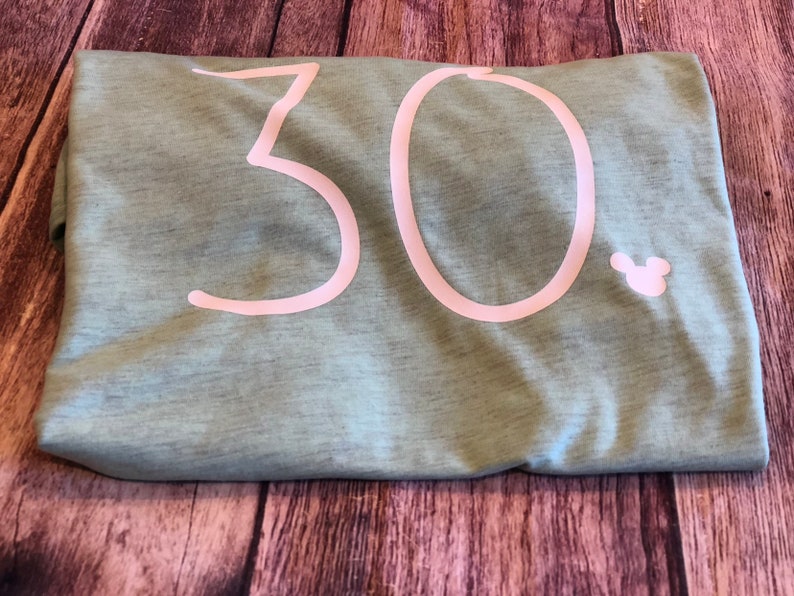 May include: A light green t-shirt with the number 30 printed in white on the front. A small white Mickey Mouse head is printed to the right of the number.