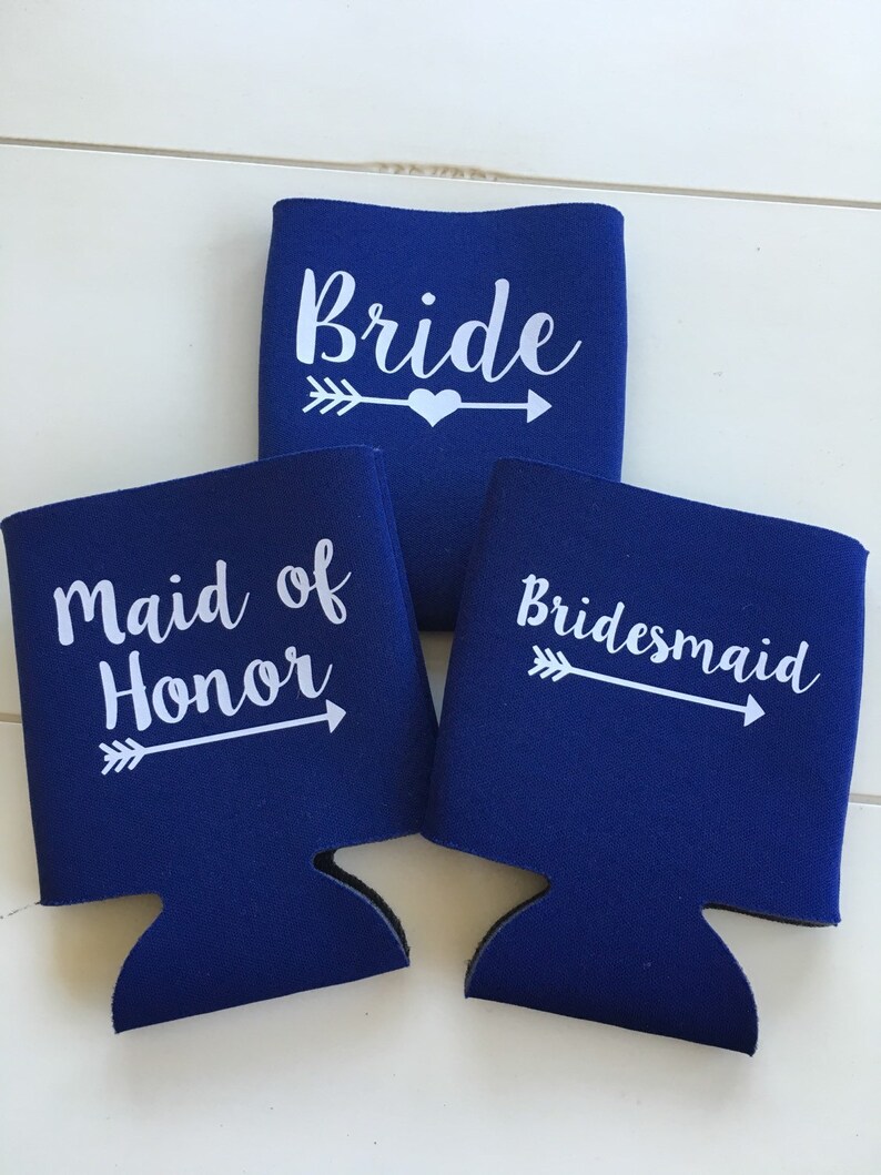 Pode incluir: Tr&ecirc;s coolers de lata azuis com texto branco e flechas. Os coolers dizem "Bride", "Maid of Honor" e "Bridesmaid".