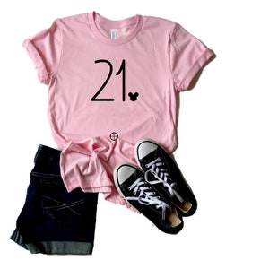 May include: Pink t-shirt with the number 21 and a small Mickey Mouse icon printed on the front.