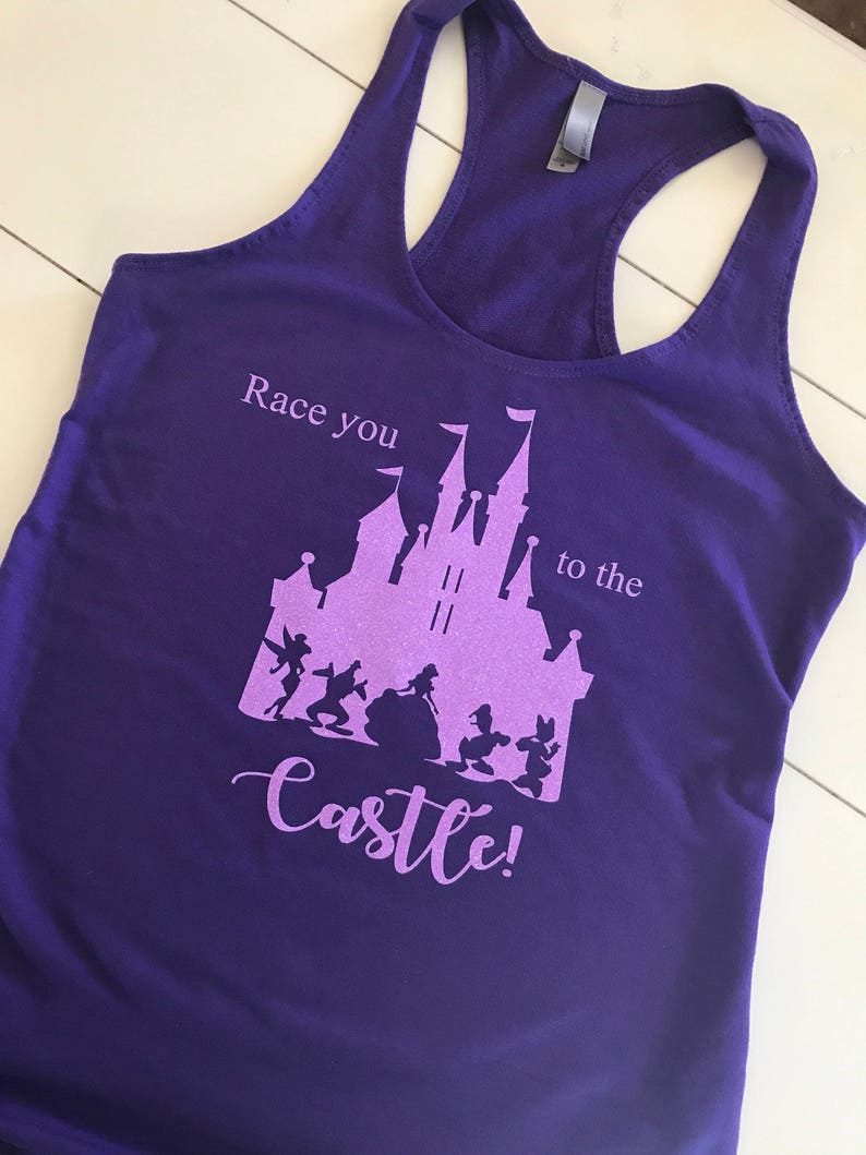 May include: Purple tank top with a pink silhouette of Cinderella's castle and characters. The text "Race you to the castle!" is printed on the shirt.