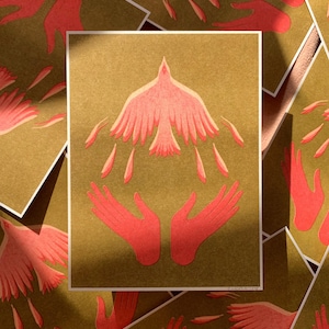 May include: A pink bird with outstretched wings is surrounded by two red hands, all on a gold background. The hands are cupped as if to hold the bird.