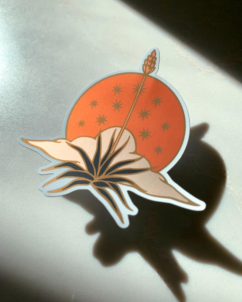 May include: A sticker with a stylized illustration of a flower with a large, white blossom and a long, thin stem. The flower is set against a background of a red circle with gold stars.
