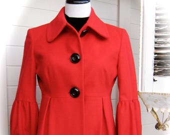 May include: A red wool jacket with a collar, button closure, and long sleeves. The sleeves have a gathered detail at the cuffs.