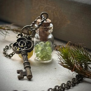 La bière de l'enchanteur. N° 22. Petite fiole steampunk remplie de pépites de péridot, pendentif avec un collier clé en or antique