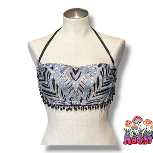 May include: A silver and black sequined halter top with a black beaded fringe. The top is on a white mannequin. The text "MadebyVibe" is in the lower right corner of the image.