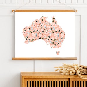 Pode incluir: Uma impressão floral rosa do contorno da Austrália em uma tela branca com uma moldura de madeira.