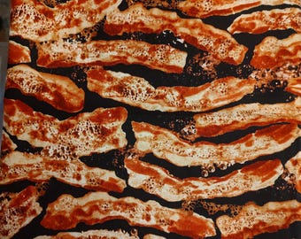 It's BACON fabric!! Black background with realistic pieces of sizzling bacon! Make an Apron, placemats! Oven mitts, tote. 1 yd x 44" W