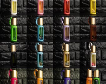 Può includere: Una collezione di sedici flaconi roll-on in vetro con tappi dorati, ciascuno racchiuso in un rivestimento in silicone colorato con un occhiello abbinato. I flaconi contengono vari liquidi ed elementi botanici in diverse tonalità vivaci.