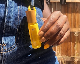 May include: A yellow glass bottle with a bamboo lid and a yellow silicone strap. The bottle is labeled "NBM cuticle buddy 5 ml".