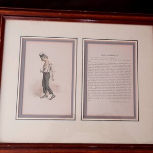 Può includere: Stampa incorniciata di un'illustrazione in bianco e nero di un giovane ragazzo che indossa un cappello a cilindro e tiene un libro. La stampa è accompagnata da un estratto di testo dal romanzo "David Copperfield" di Charles Dickens.
