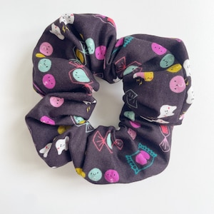 May include: A dark brown scrunchie with a colourful print of candy, teeth, and smiley faces.