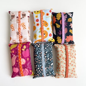 May include: Six rectangular fabric tissue box covers with various patterns. Designs include coffee cups, pumpkins, autumn leaves, apples, and floral prints. Each cover has a coordinating fabric band.