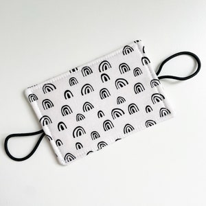 May include: A white fabric face mask with black rainbow print and black elastic ear loops.