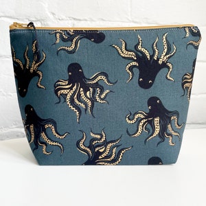 May include: A blue zippered pouch with a repeating pattern of black octopus illustrations with yellow accents.