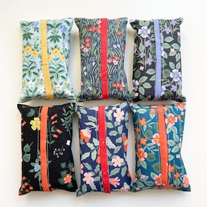 Peut inclure: Six étuis à mouchoirs rectangulaires en tissu disposés sur deux rangées. Chaque étui présente un motif floral distinct dans des tons bleu clair, vert foncé, noir et bleu marine, avec une bande de tissu verticale unie au centre.