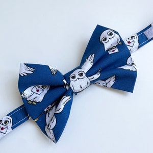May include: A blue bow tie featuring a white owl pattern. The owls are holding letters and have a whimsical design.