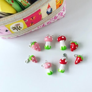 May include: A selection of miniature charms shaped like strawberries and mushrooms. The charms are painted in vibrant colours: red, pink, white, and green. Each charm has a silver-coloured clasp.
