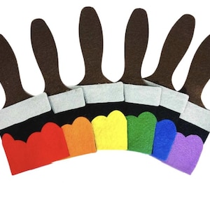 May include: A collection of felt paintbrushes in a rainbow of colors. Each brush has a brown handle, a white ferrule, and a black brush head with a scalloped edge in red, orange, yellow, green, blue, and purple.