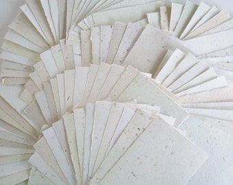 May include: A collection of handmade paper sheets in various shades of white and cream. The paper has a textured surface and is made from recycled materials.