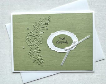May include: A green sympathy card with a white oval that says "With Sympathy" and a white ribbon. The card has an embossed design of a rose and leaves.