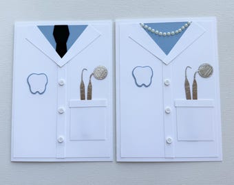 May include: Two white greeting cards designed to resemble a dentist's coat. One card features a black tie, the other a pearl necklace. Each card has a blue tooth outline, dental tools, and a pocket.