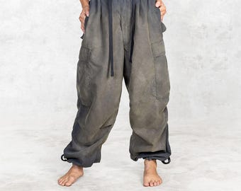 May include: Gray cargo pants with a faded, ombre effect. The pants have a drawstring waist, pockets on the sides, and drawstrings at the ankles. The fabric appears to be a soft, lightweight material.
