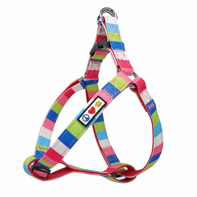 May include: A colourful striped dog harness featuring a peace sign and paw print design. The harness is made from soft, durable fabric and has a secure buckle fastening.