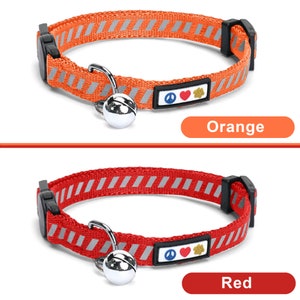May include: Two cat collars with a bell and a peace sign, heart, and paw print charm. The collar on top is orange with reflective stripes and the collar on the bottom is red with reflective stripes. The text "Orange" is below the top collar and the text "Red" is below the bottom collar.